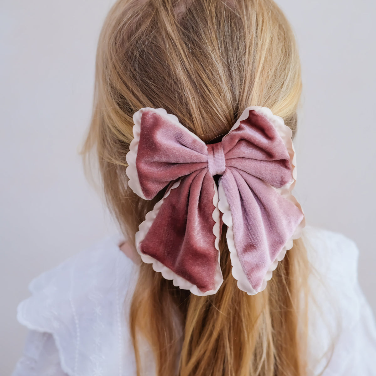 Young girl wearing scalloped edge velvet bow hair clip