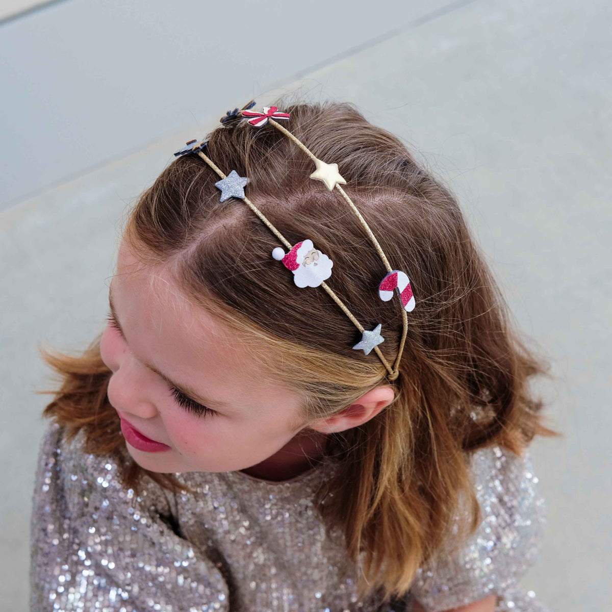 Child wearing gold Christmas double headband with festive charms