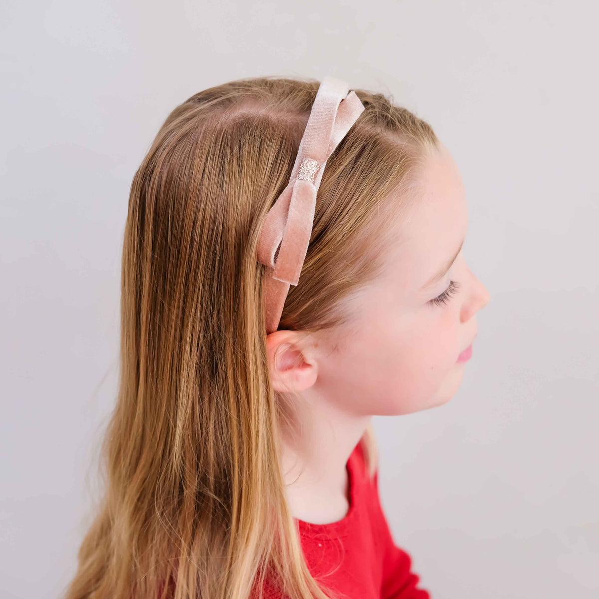 Young girl wearing pink velvet bow headband