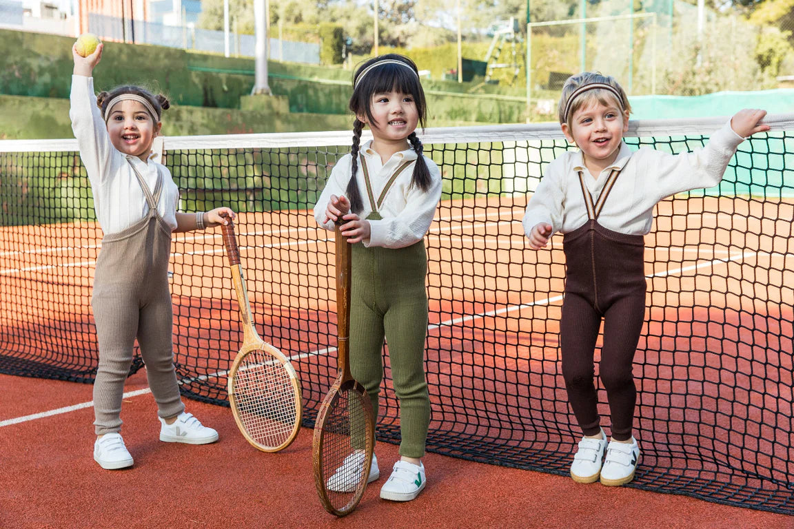 Toddlers wearing Silly Silas cotton tights with suspenders on a tennis court
