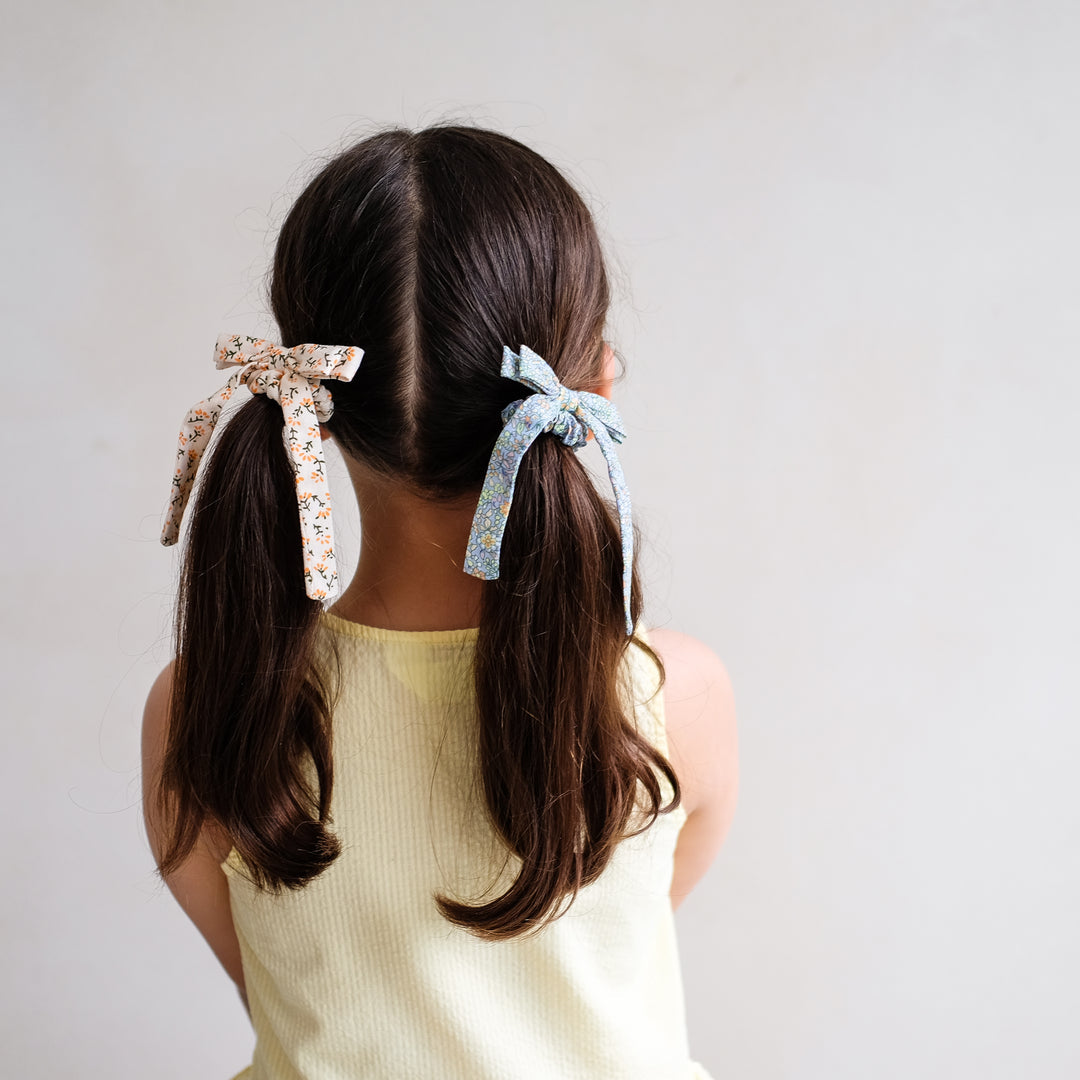 girl wearing Mimi and Lula floral bow scrunchies
