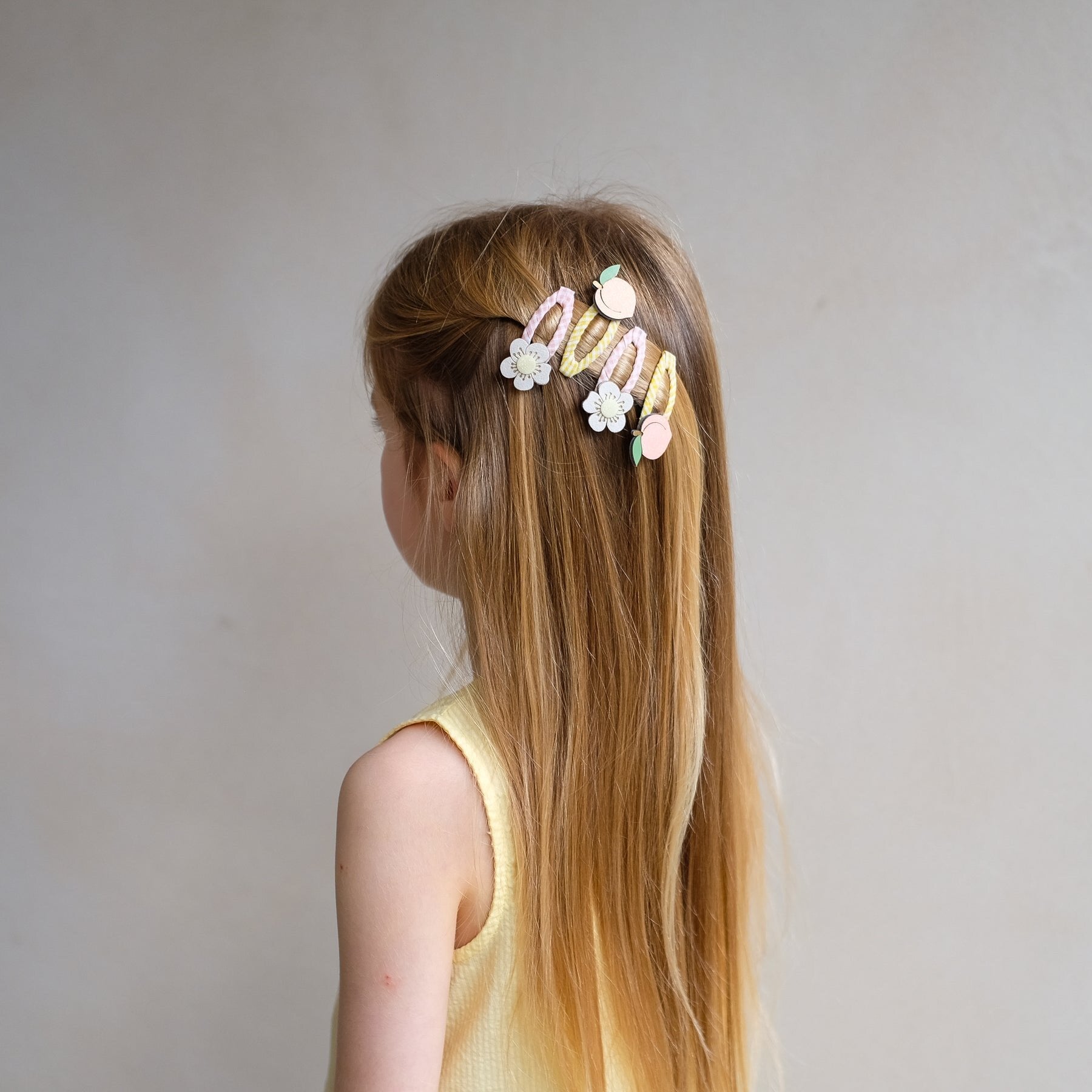 girl wearing Mimi and Lula peach and flower hair clips