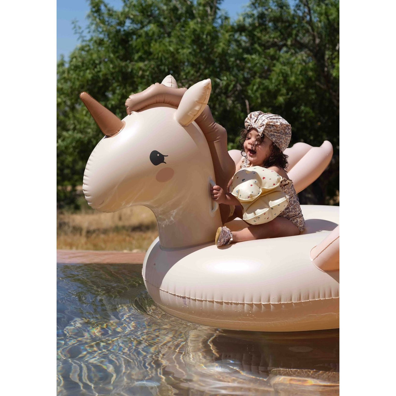 kids using Konges Sløjd unicorn pool float in swimming pool