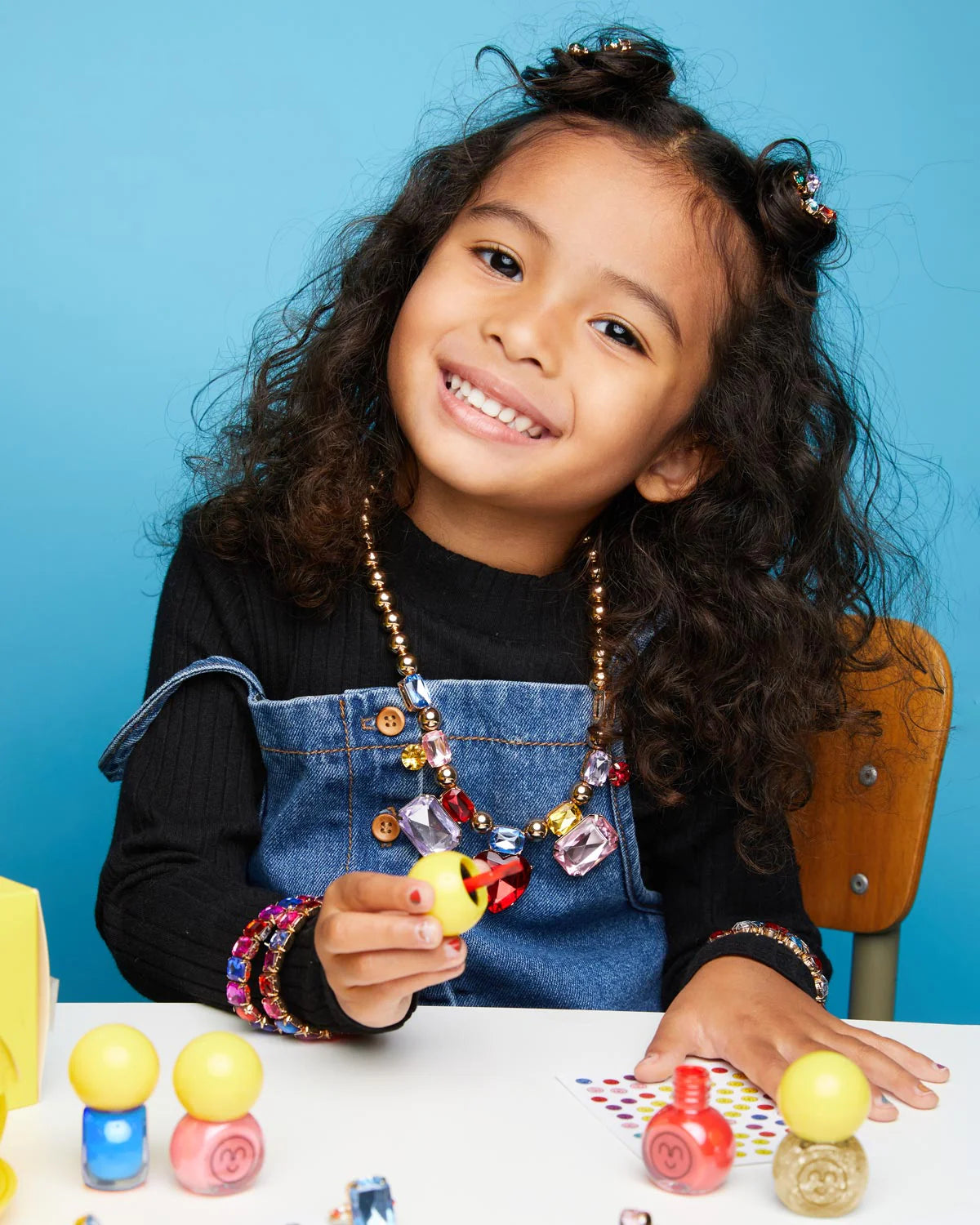 Child playing with Super Smalls Self Care Nail Kit and colorful nail art accessories