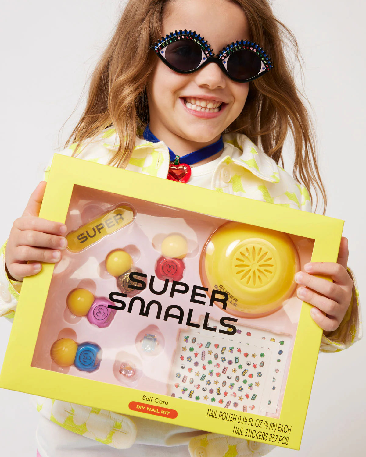 Child holding Super Smalls Self Care Nail Kit in yellow packaging