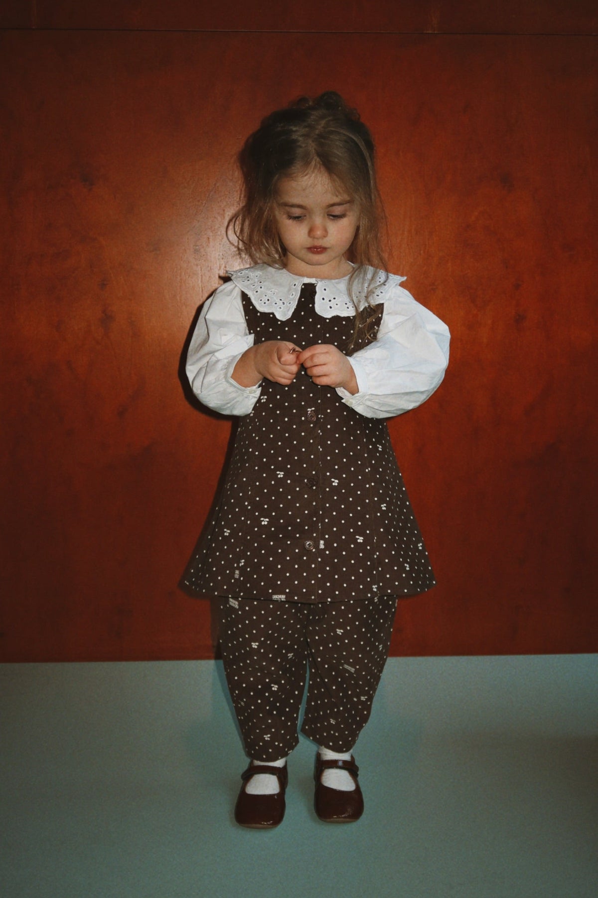 Toddler wearing the cherry-dot Cara dress over a white ruffle-collar blouse