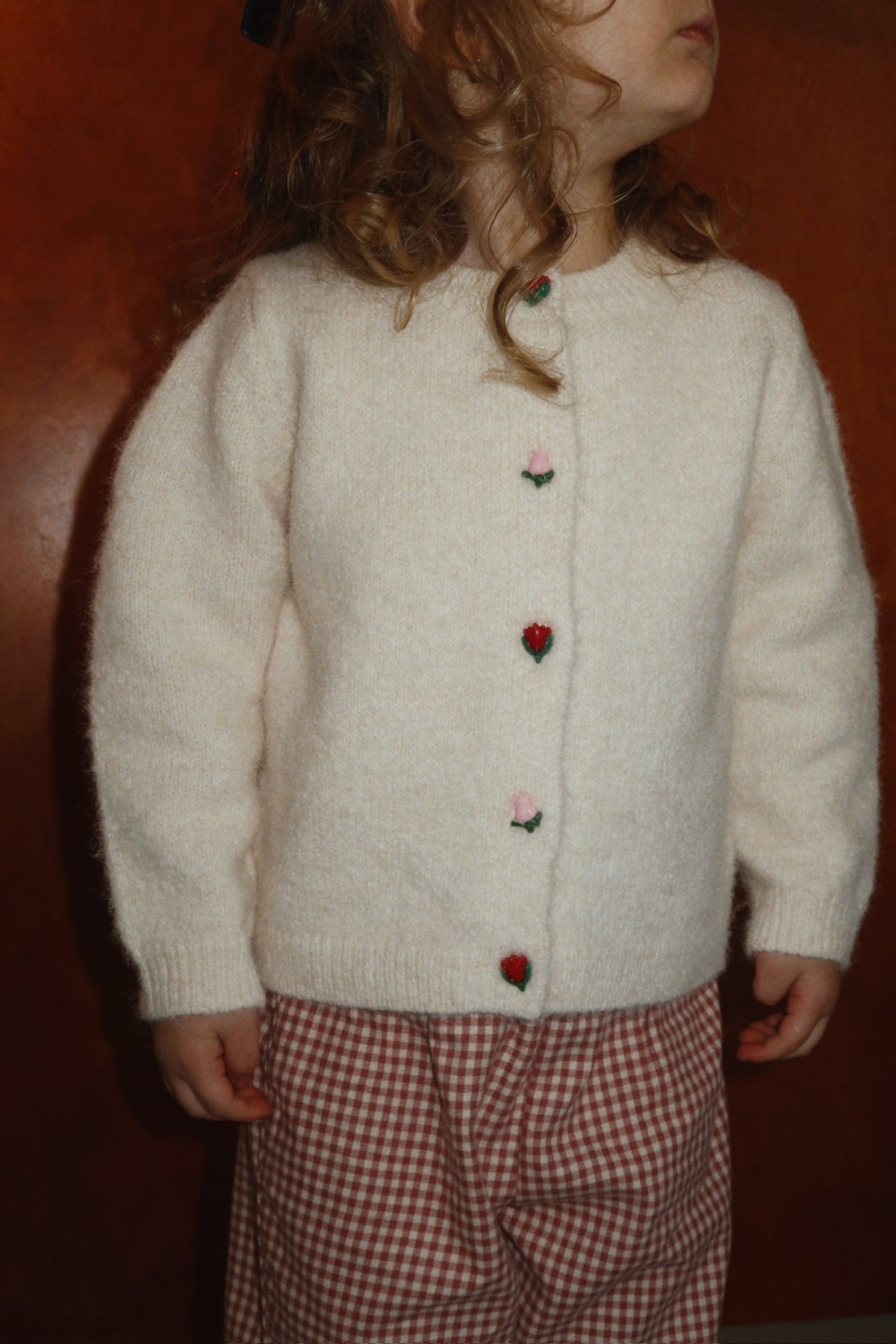 Child wearing the buttercream Fleuri cardigan buttoned up, front view