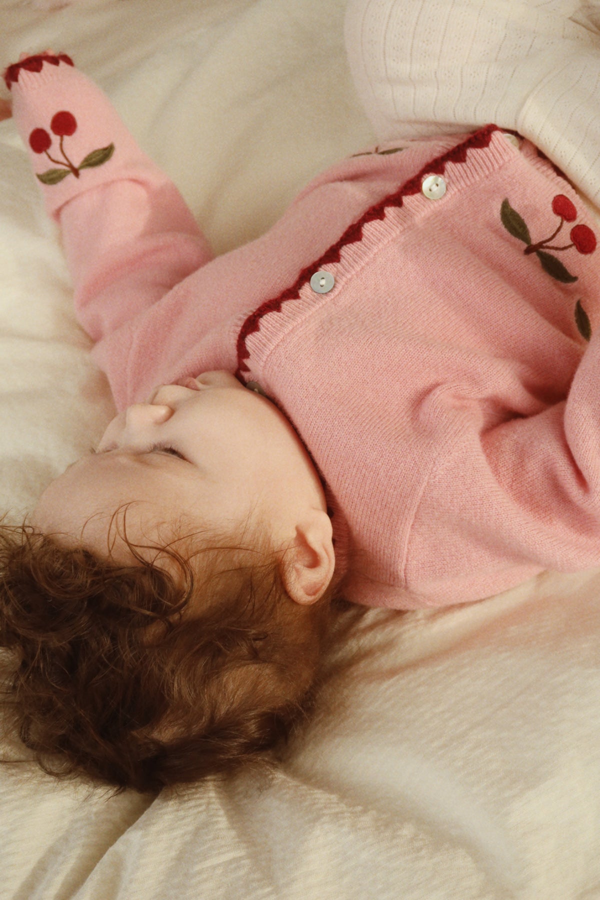 Close-up of a baby wearing the Collette cardigan with embroidered cherries