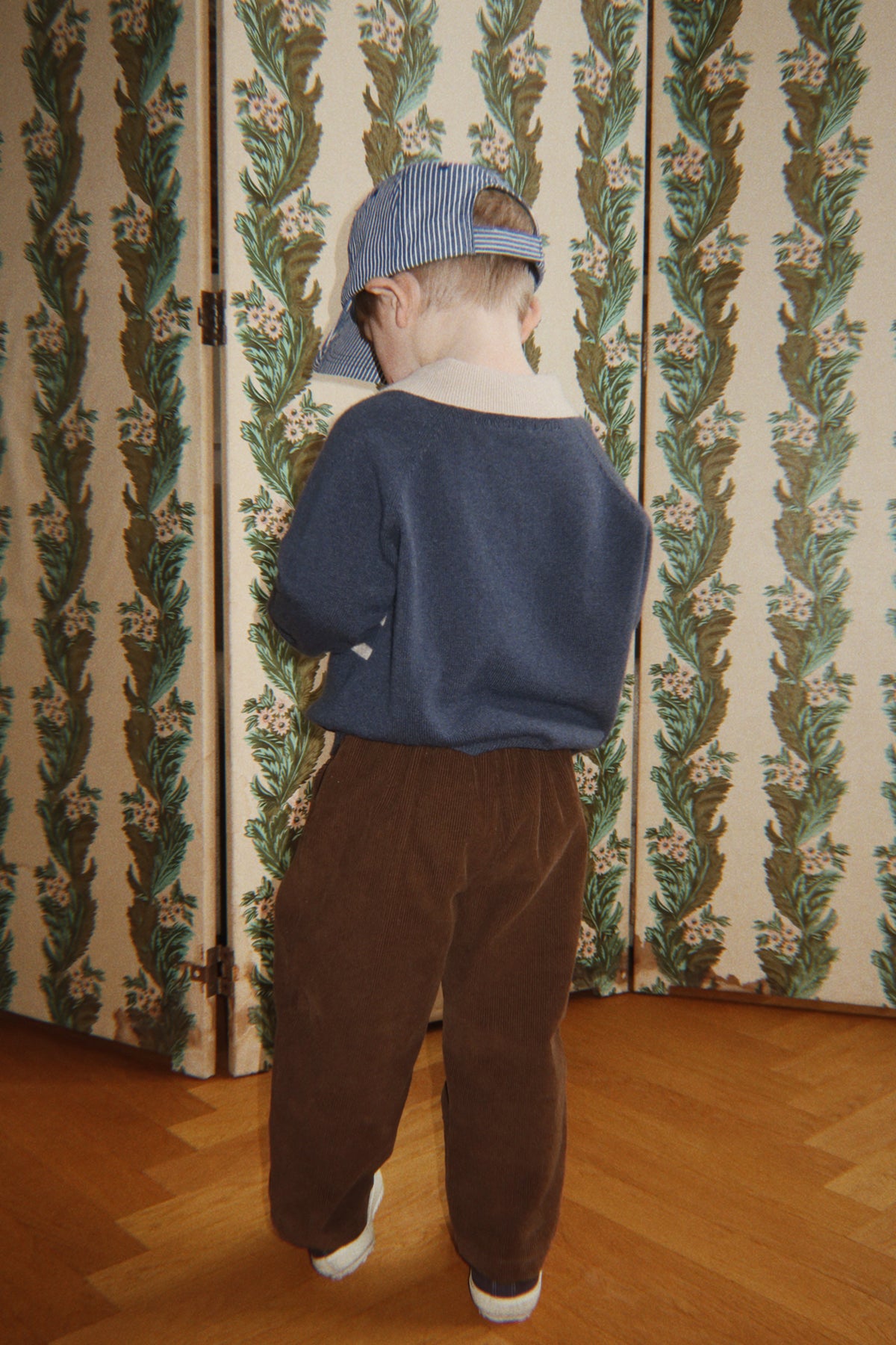 Child seen from behind in the navy Basi polo and brown pants
