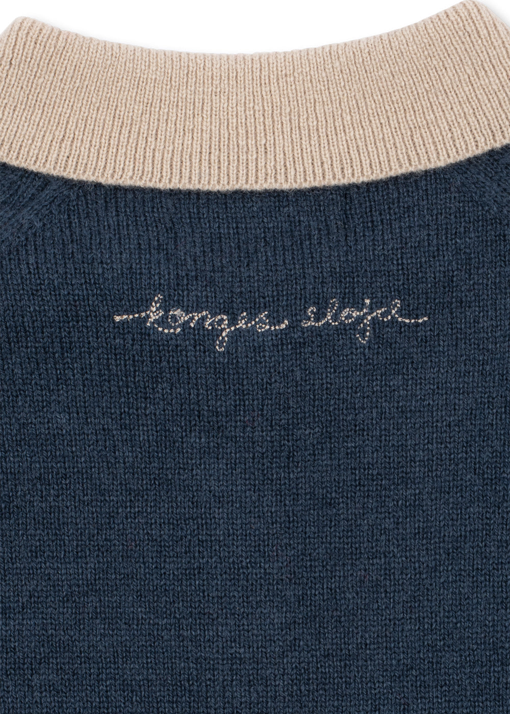 Close-up of the embroidered Konges Sløjd script on the navy knit