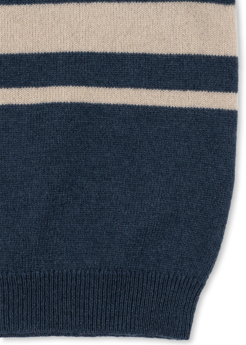 Close-up of the ribbed hem and chest stripes on the navy knit polo