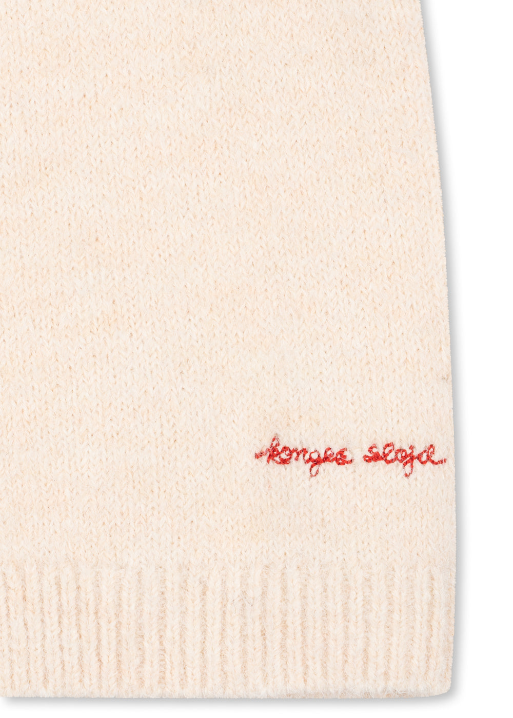 Close-up of the red embroidered Konges Sløjd script at the cardigan hem