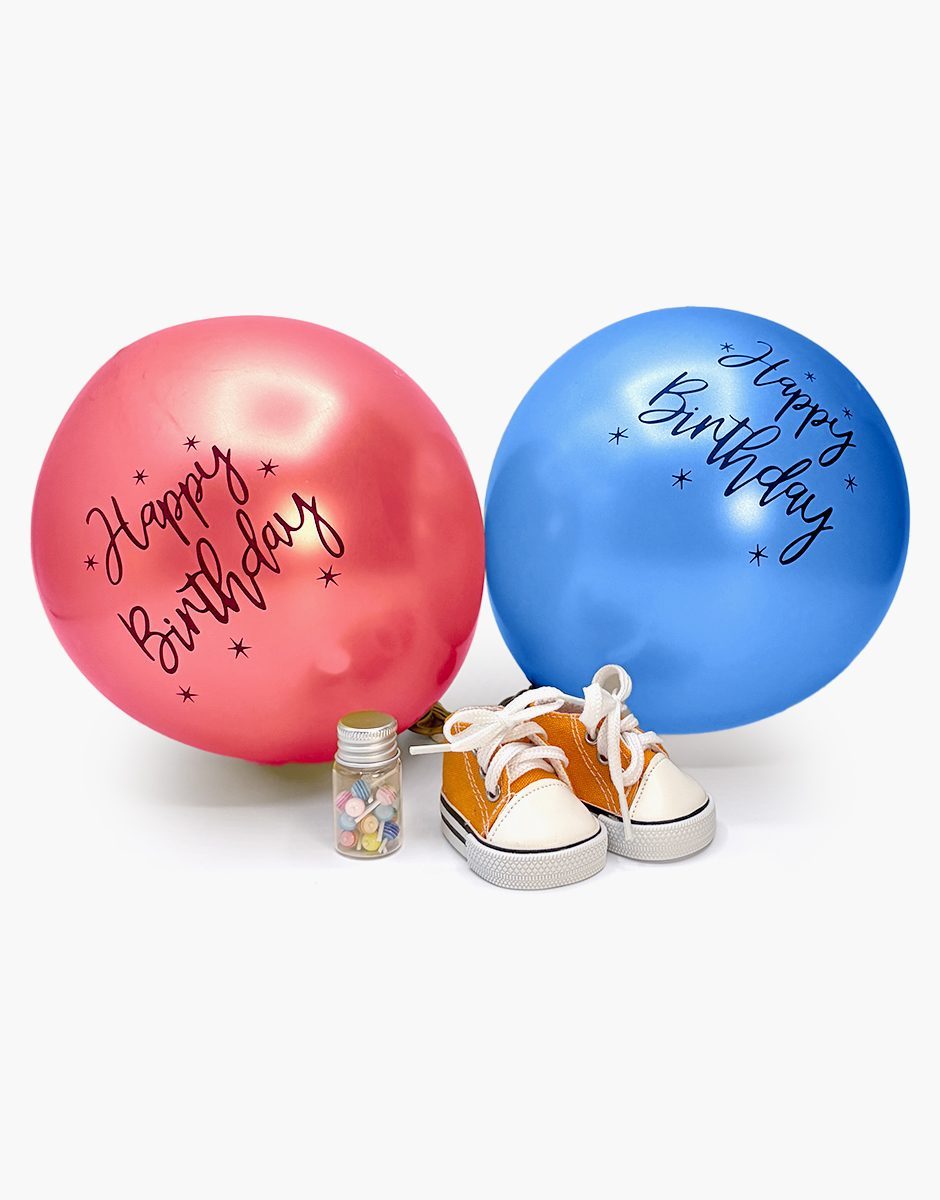 Mini Panchas birthday accessory set with orange Komvers sneakers, lollipop jar and Happy Birthday balloons by Minikane