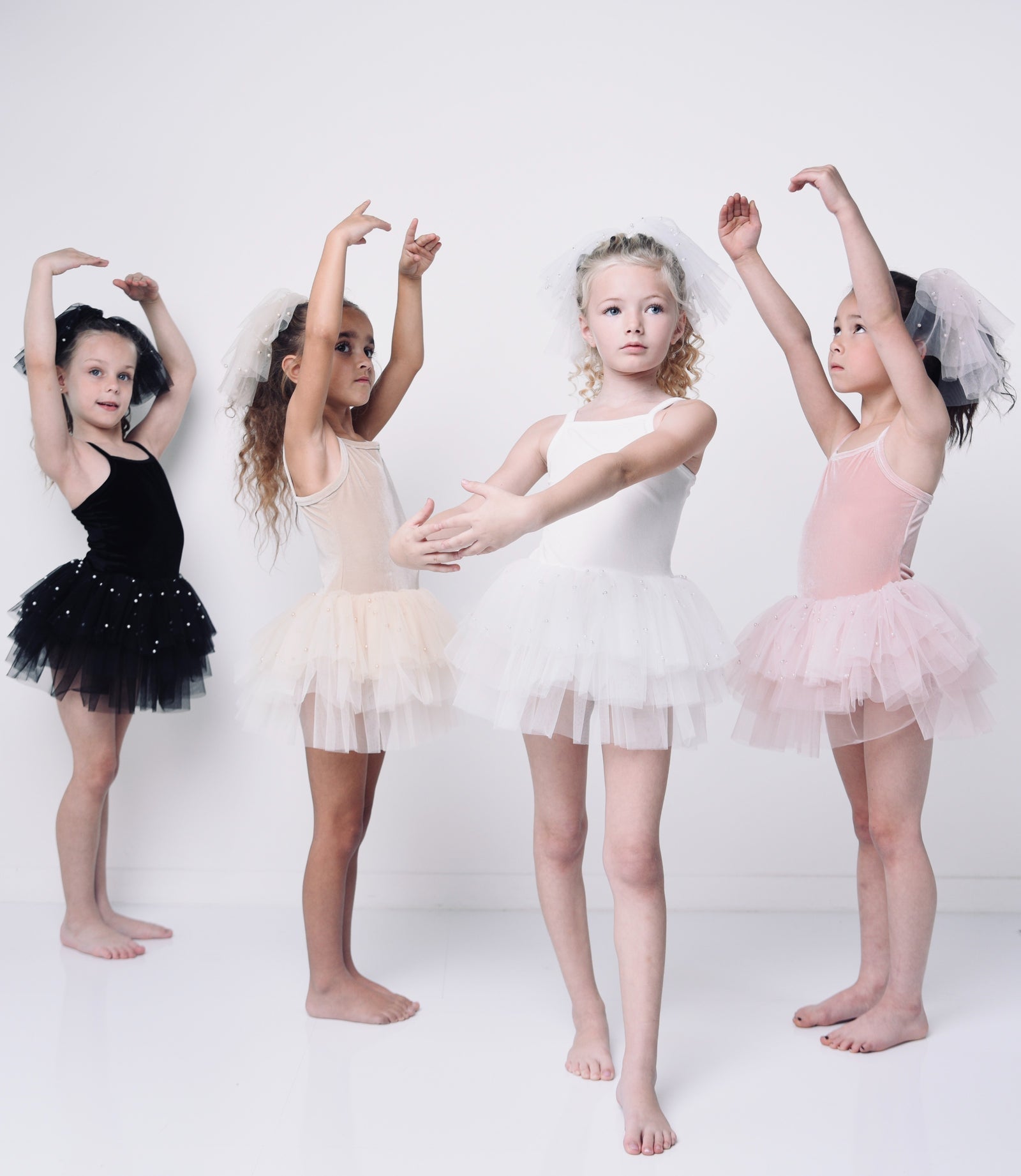 Four girls in ballet tutus dancing — black, beige, white, and pink tutu dresses — at littlewild kids