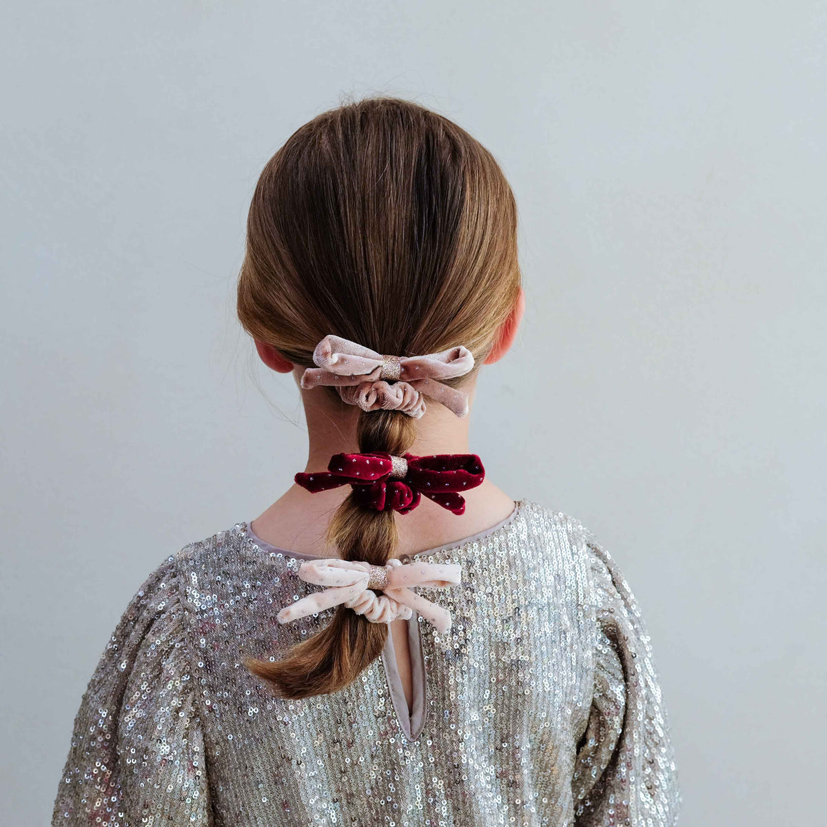 Young girl wearing velvet bow scrunchies