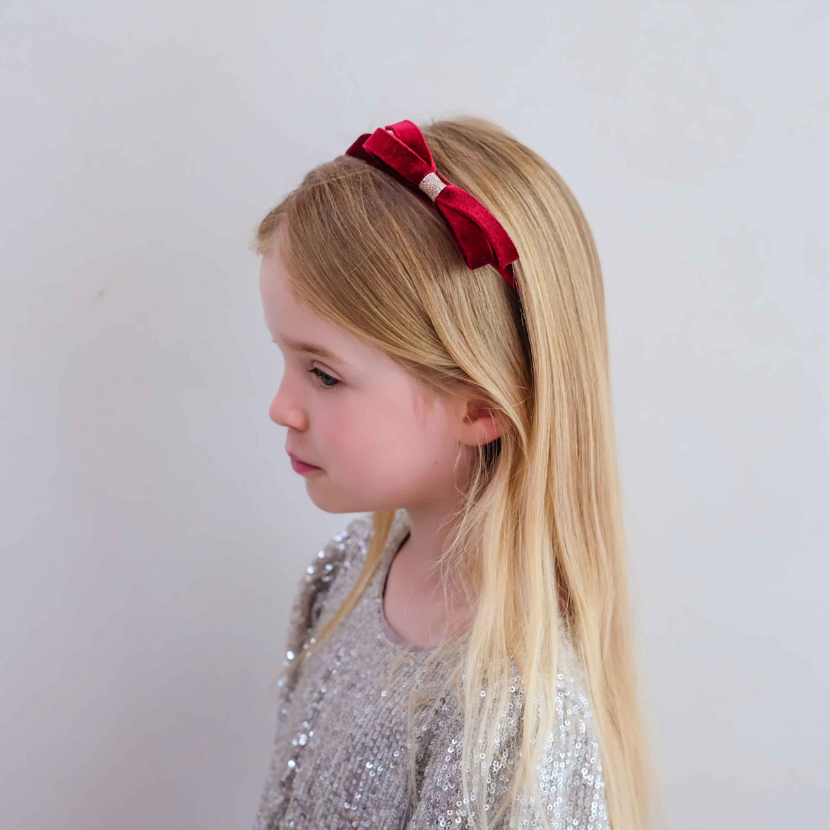 Young girl wearing burgundy velvet bow headband