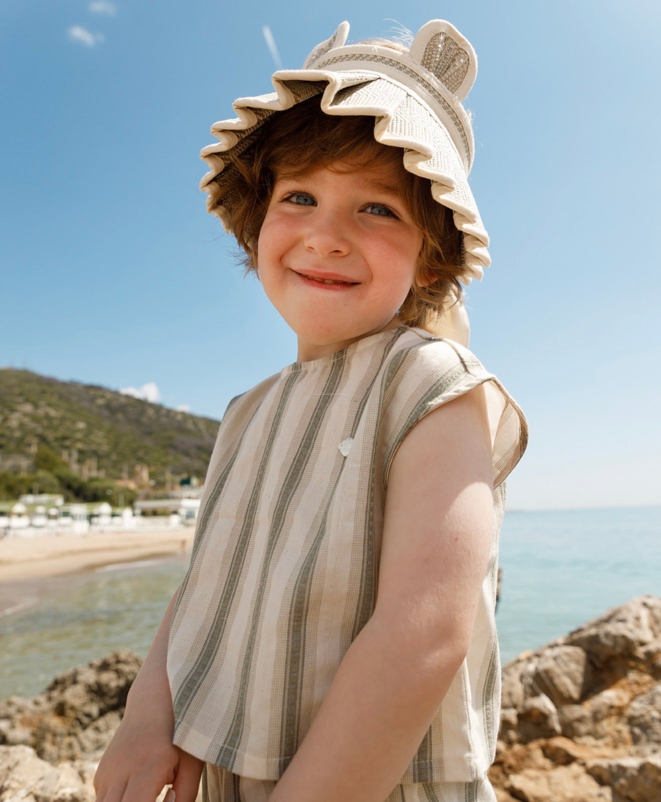 Child wearing LORNA MURRAY × OZOONZ ozbear straw sunvisor outdoors