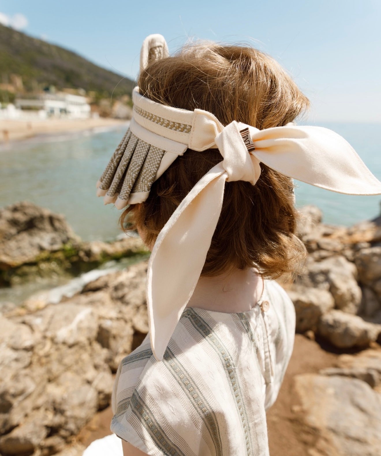 Back view of child wearing LORNA MURRAY × OZOONZ ozbear sunvisor showing the ribbon tie