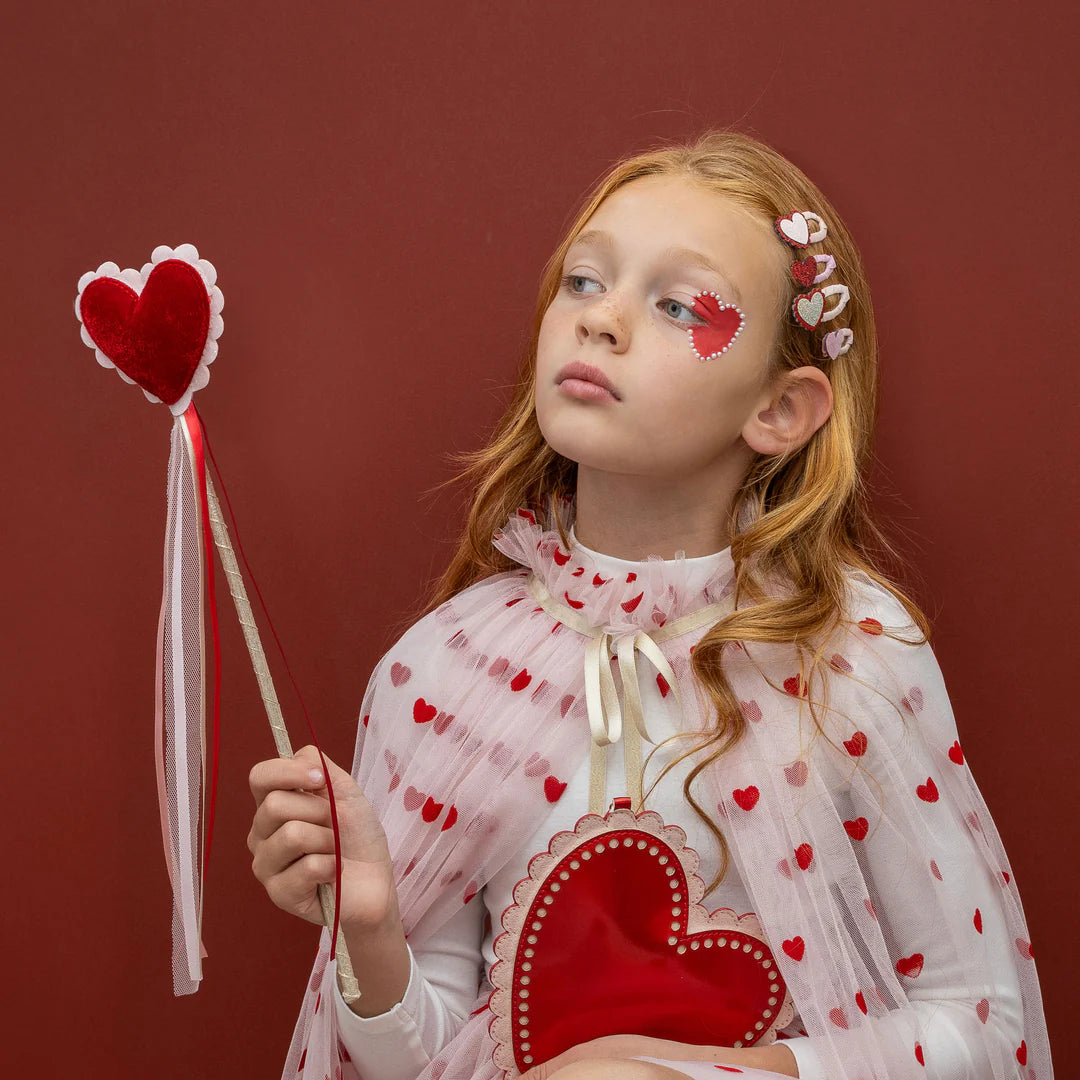 Child wearing Mimi & Lula heart print outfit and holding a heart wand for Valentine's Day