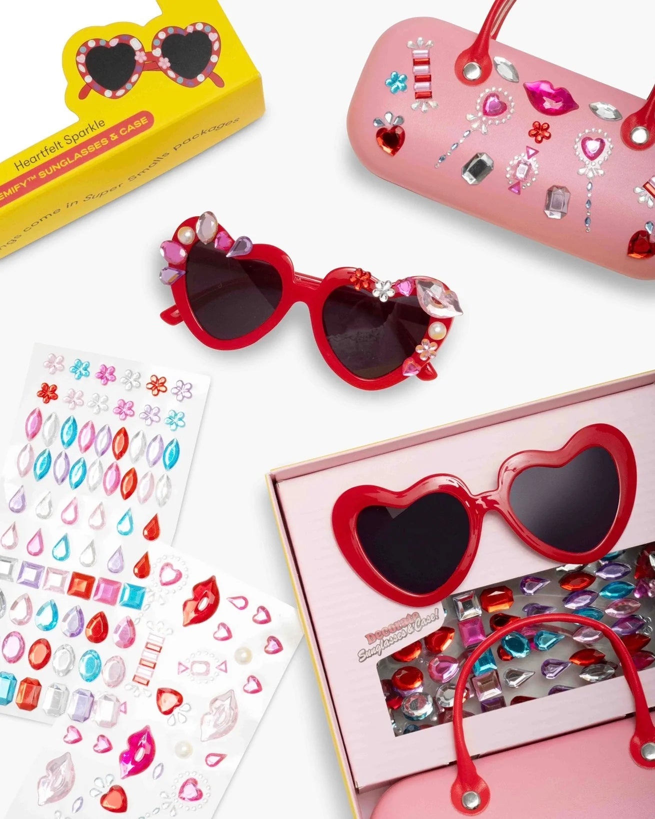 Supersmalls Heartfelt Sparkle Gemify Sunglasses and Case — heart-shaped kids sunglasses with sparkly pink case and gem stickers, flat lay on white background