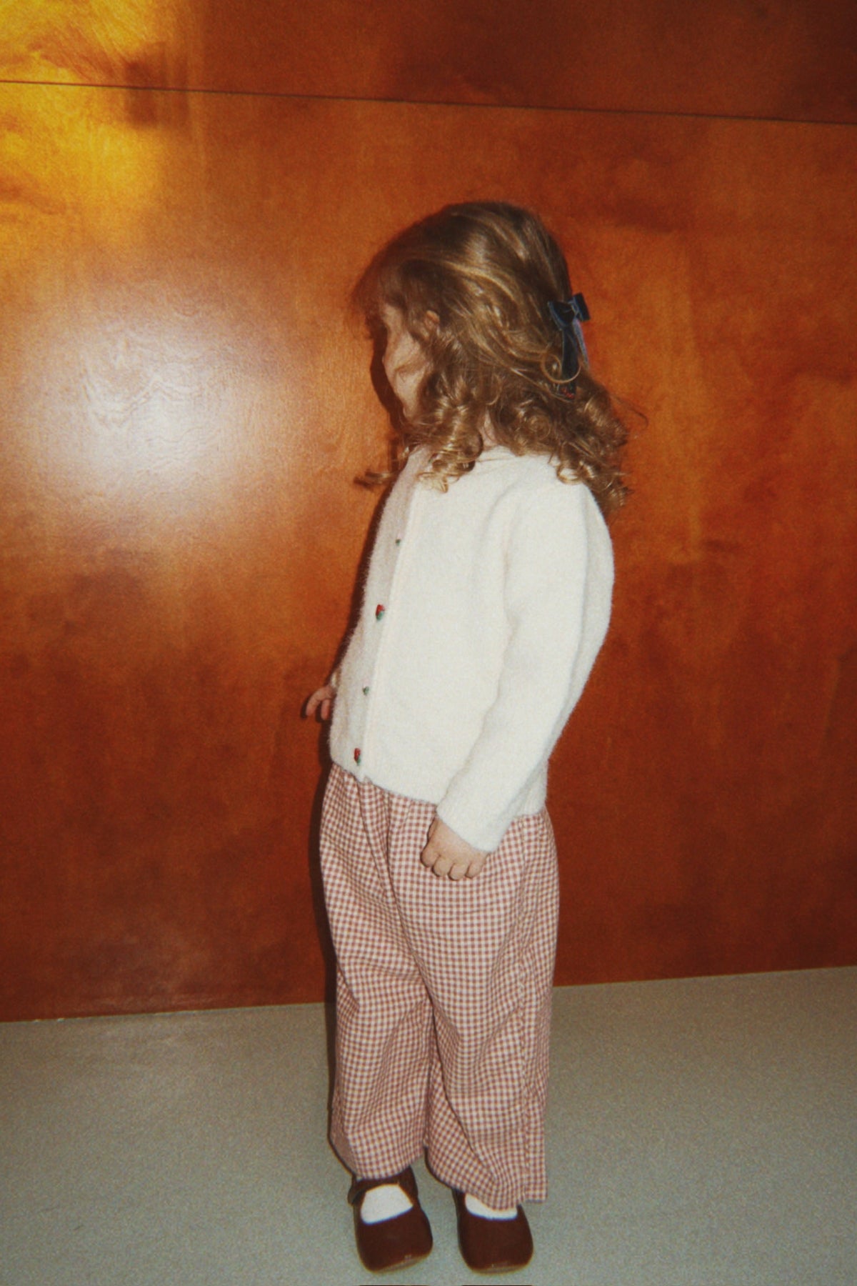 Girl wearing the cream Fleuri cardigan with red gingham pants