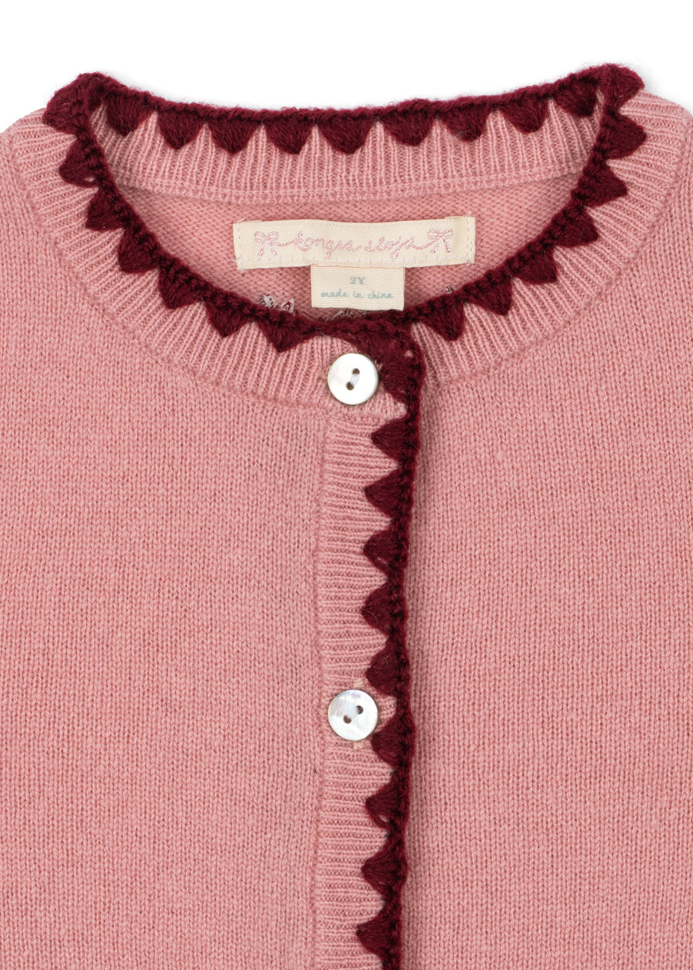 Close-up of the scalloped burgundy trim and front buttons on the wool cardigan