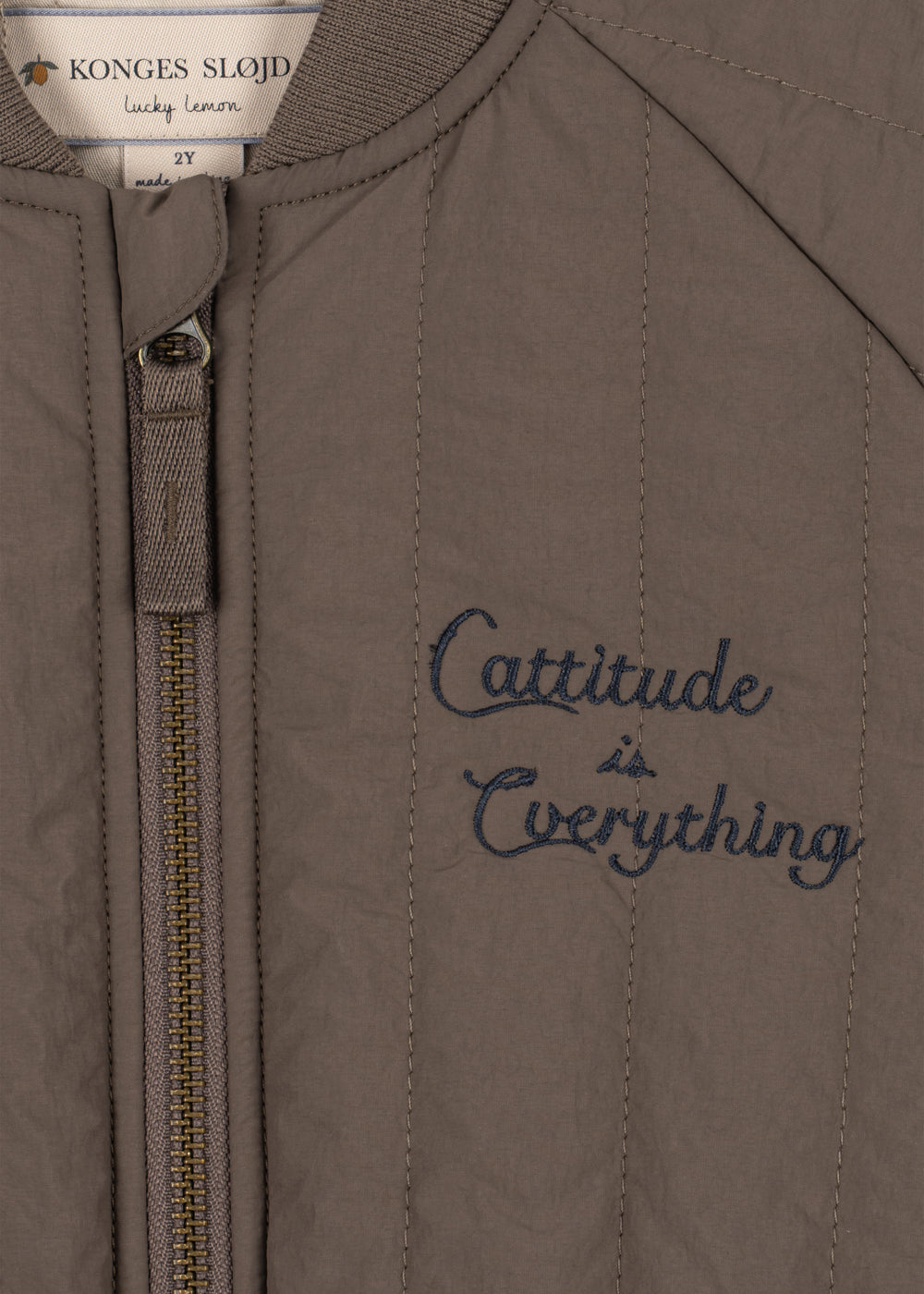Close-up of the front zip and embroidered script on the walnut bomber