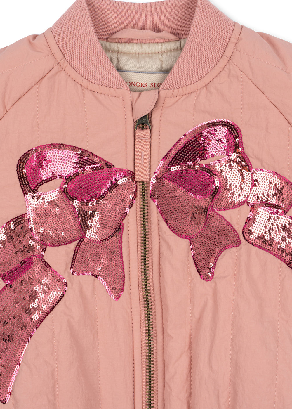 Close-up of the large pink sequin bow and front zip on the Juno bomber
