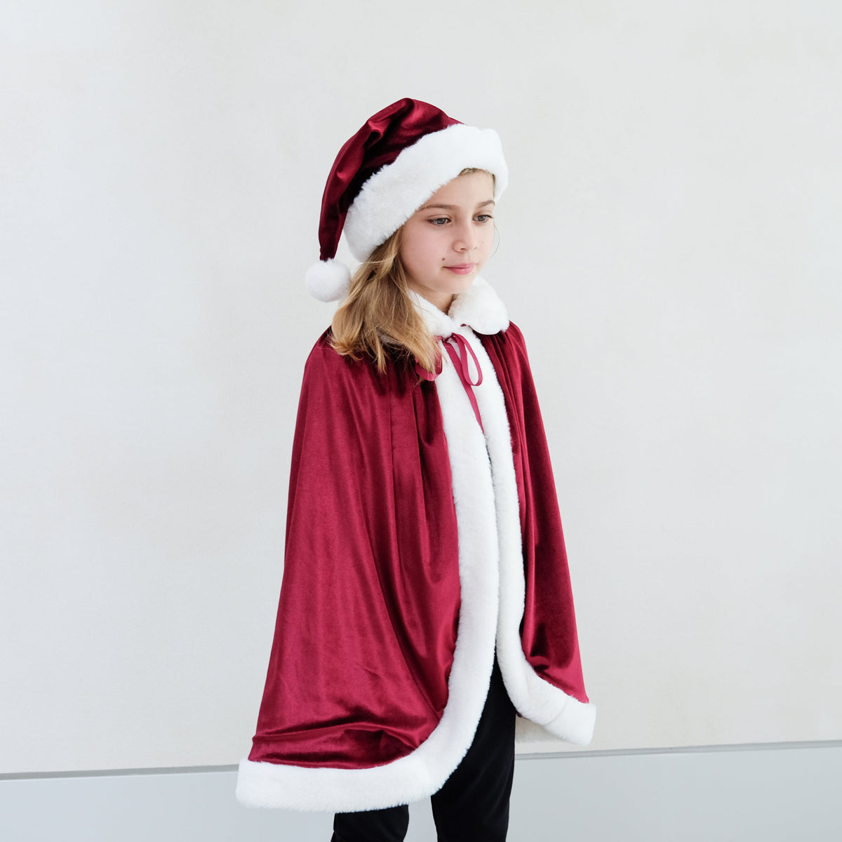 Child wearing red velvet Santa hat with Mrs Claus cape
