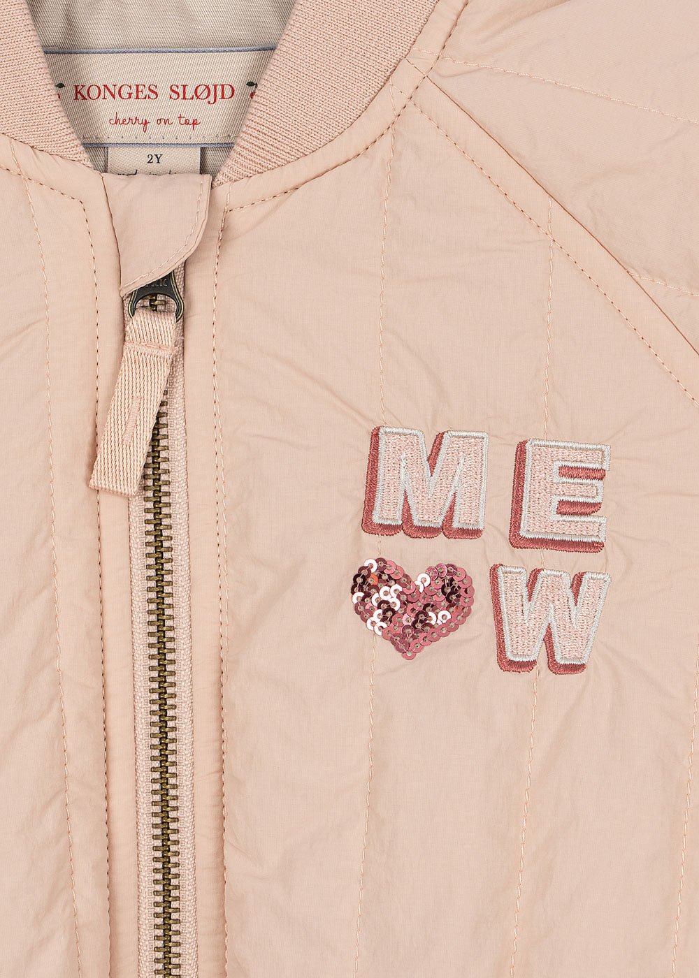 Close-up of Konges Sløjd Juno Kitty bomber jacket zipper and embroidered detail in Cameo Rose