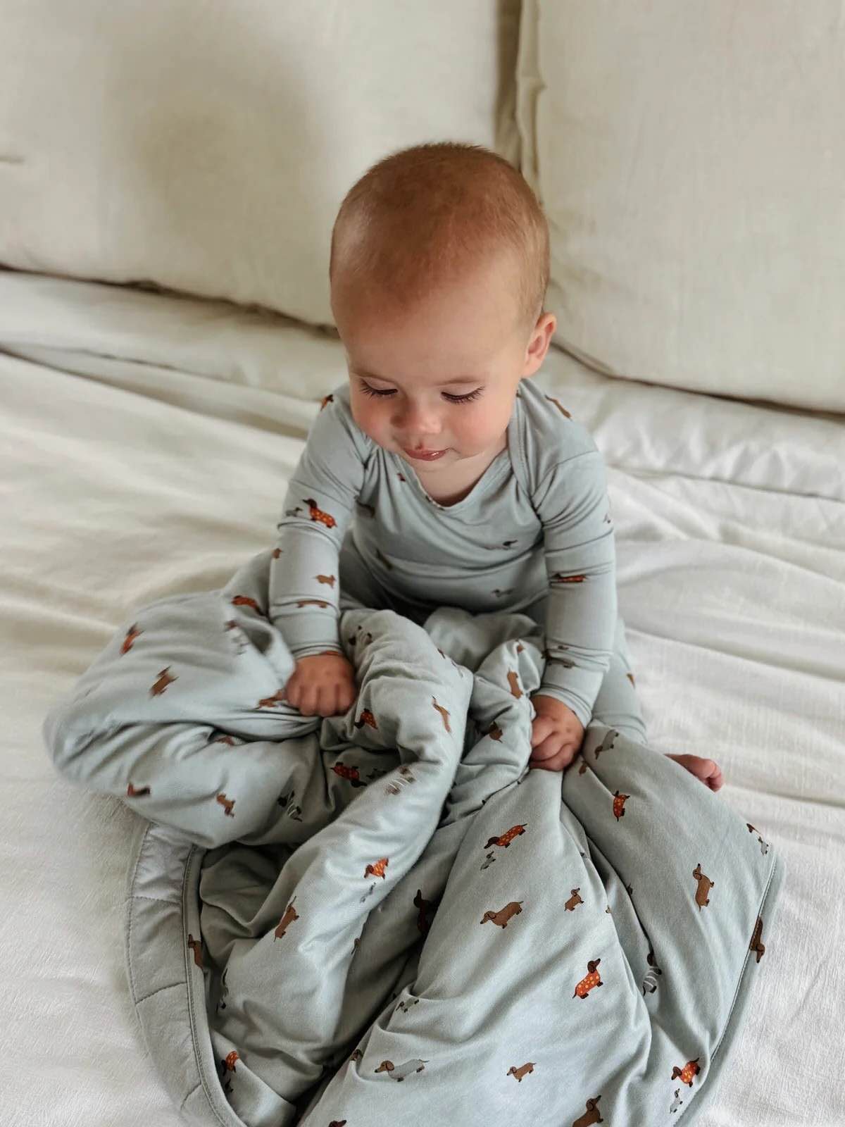gūnamūna Cloud Blanket Woof 1.0 TOG — soft blue dog print baby blanket shown on infant, lightweight and breathable